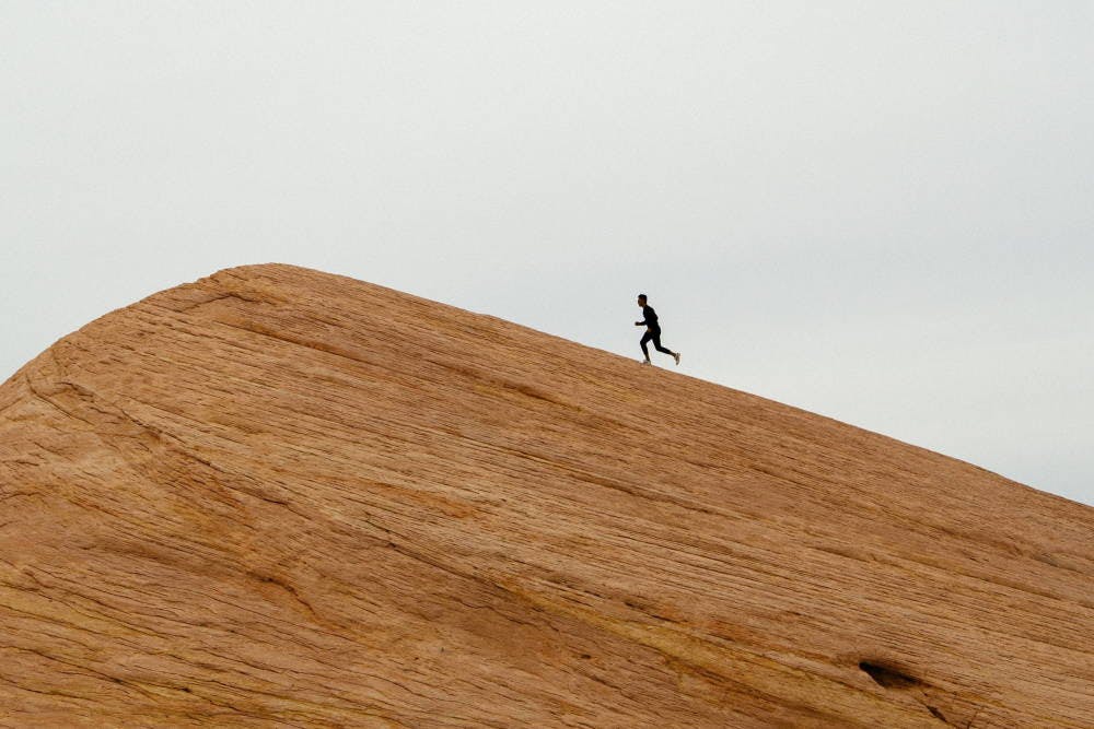 Someone running up a sand dune