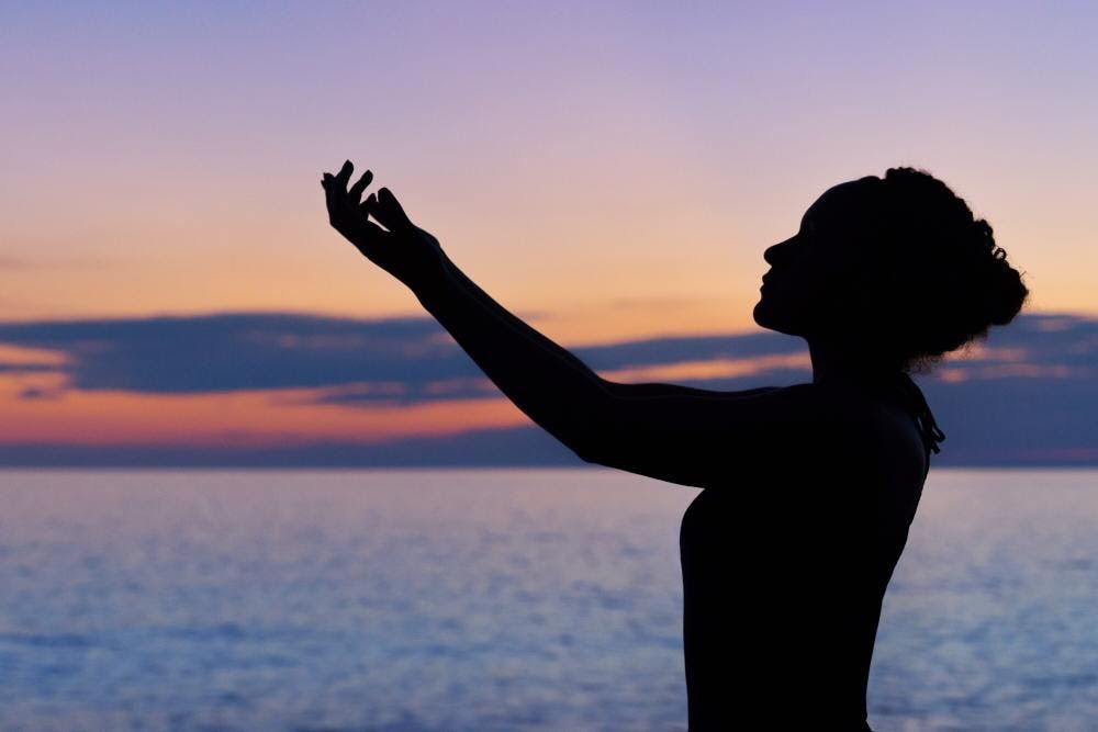 Women meditating in front of sunset